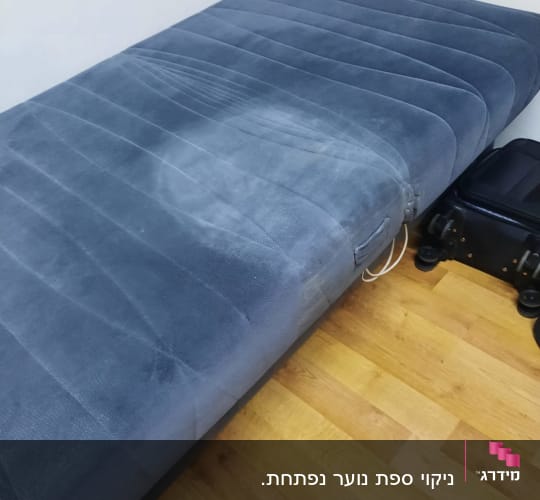 מזרן כחול עם כתם על רצפת עץ